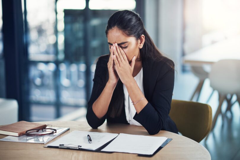 A business woman puts her head in her hands after making a mistake
