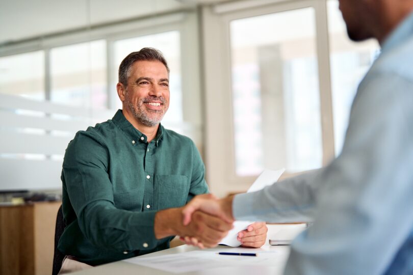 A smiling man shakes hands because he has made the decision between bank vs mortgage broker