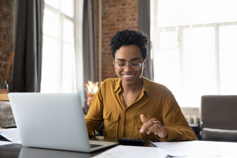 a happy smiling woman learns about loan-to-value ratio mortgage options on her computer
